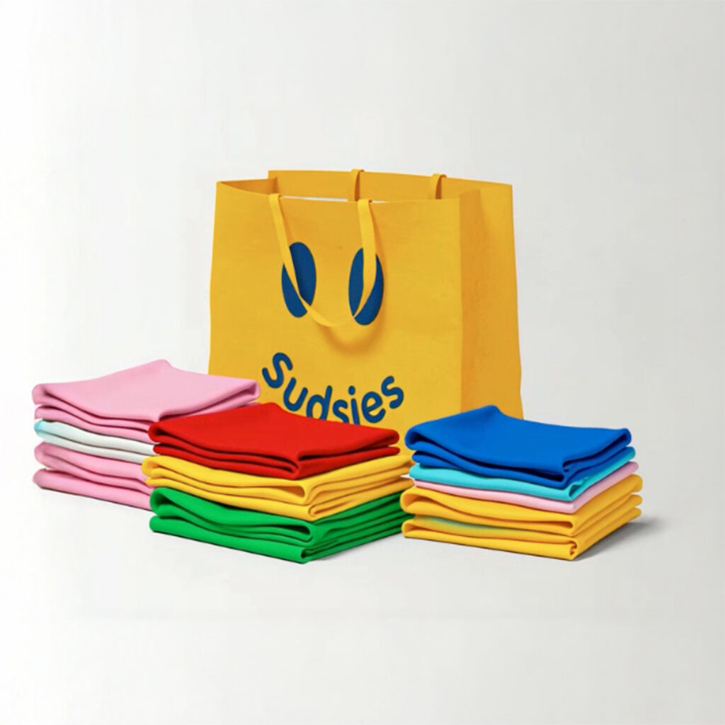 Neatly folded colorful garments displayed beside Sudsies branded bag
