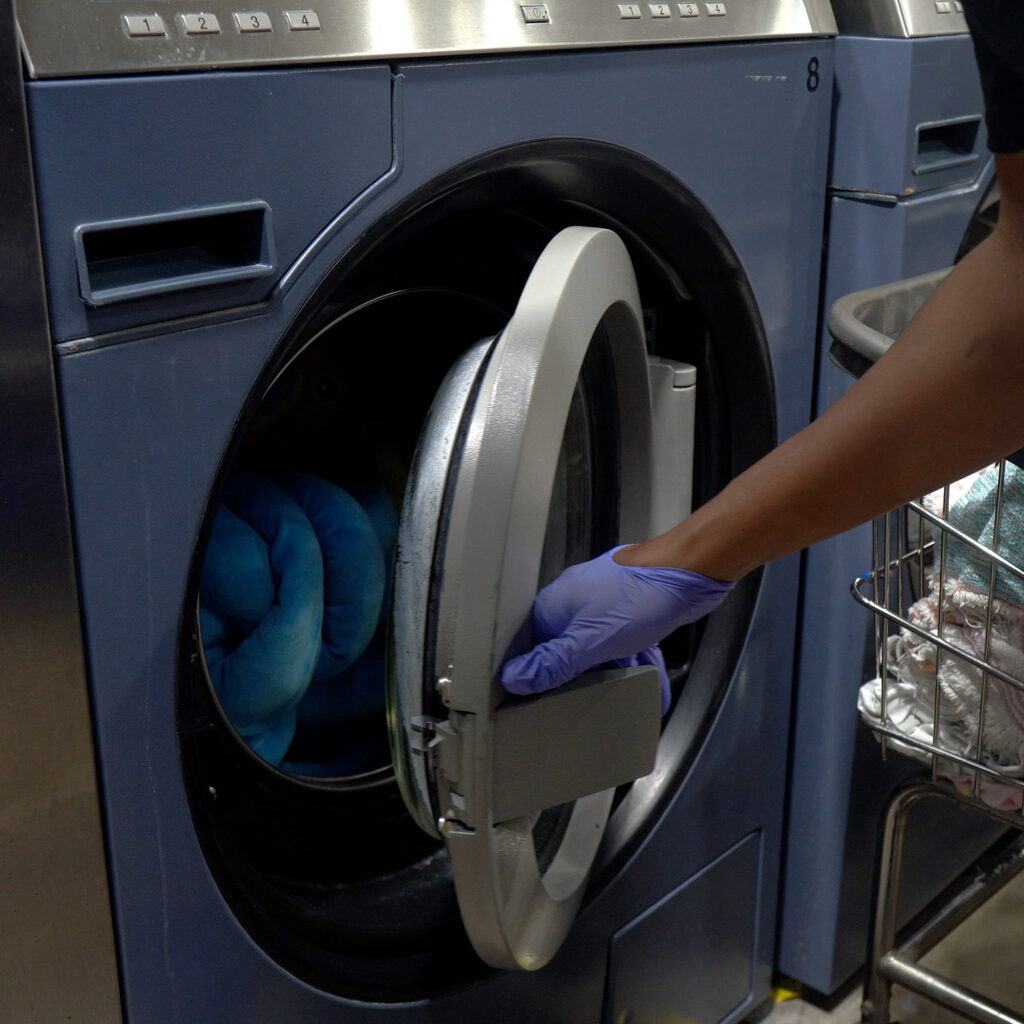 Sudsies team member loading garments into commercial washing machine